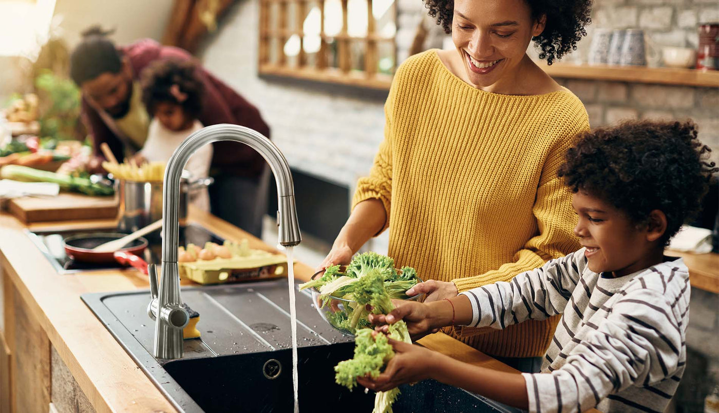 Family using 4N1 kitchen faucet filtered water to wash vegetables